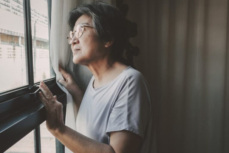 Woman looks anxiously out her window.