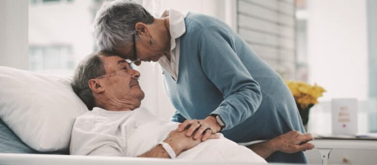 Patient in hospital being comforted by wife.