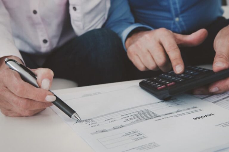 Close-up on hands of couple using pen and calculator.