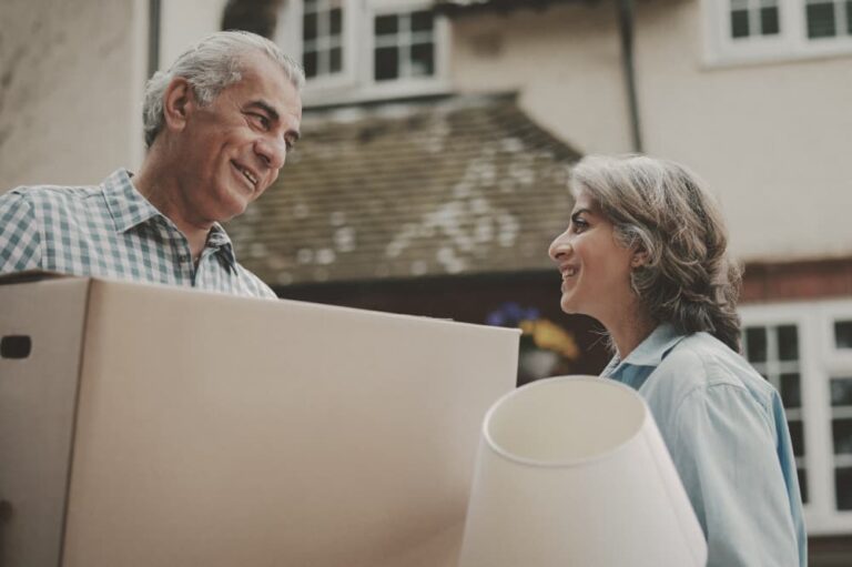 Couple holding a moving box and a lamp.