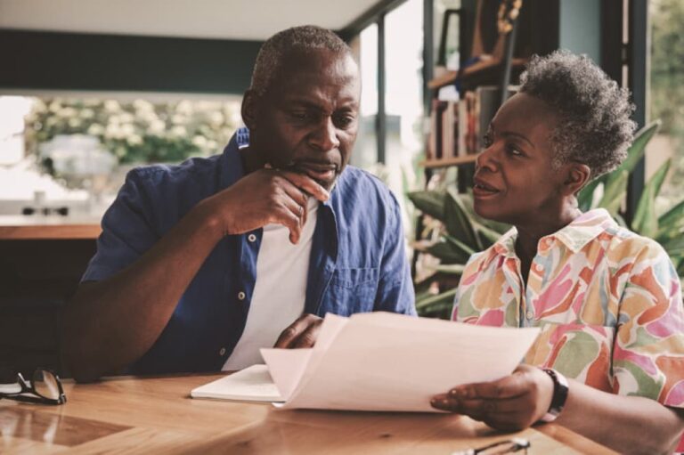 Couple examining paperwork together at kitchen table.