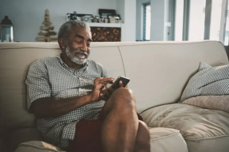 Man relaxing on couch, using phone.