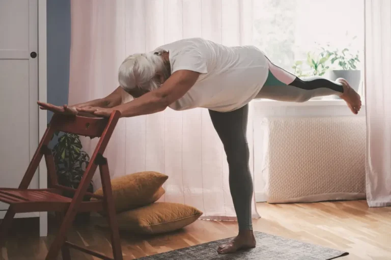 Senior doing a low impact stretching exercise with a chair.
